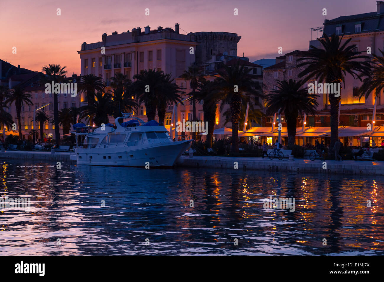 The sun sets over split riva in croatia dalmatia. the lights from the cafes and setting sun are reflected in the water Stock Photo