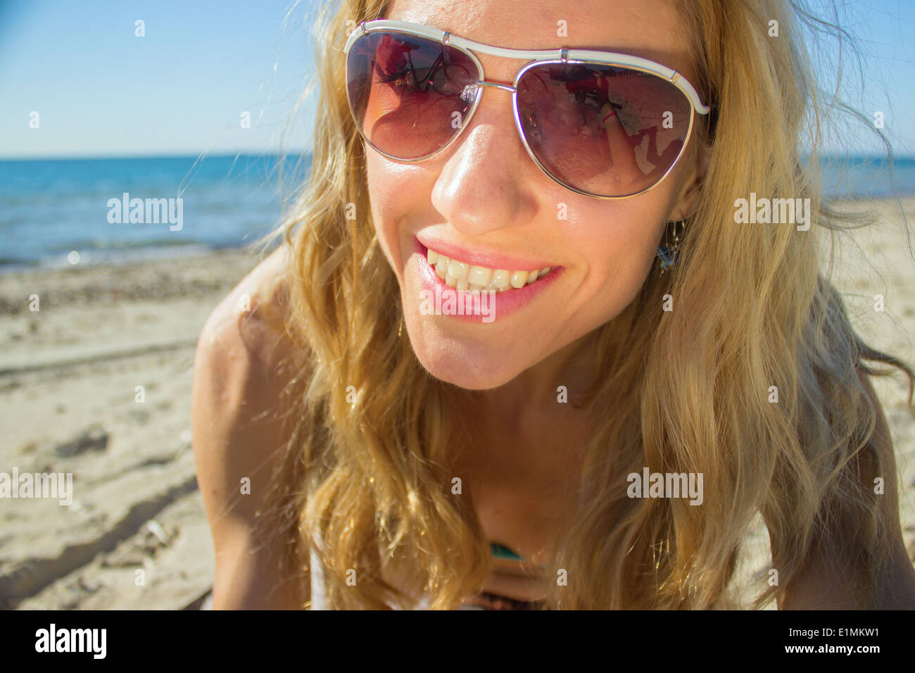 woman face beach sea sunglasses bright vivid pink holding sunglasses summer blond air blonde Stock Photo