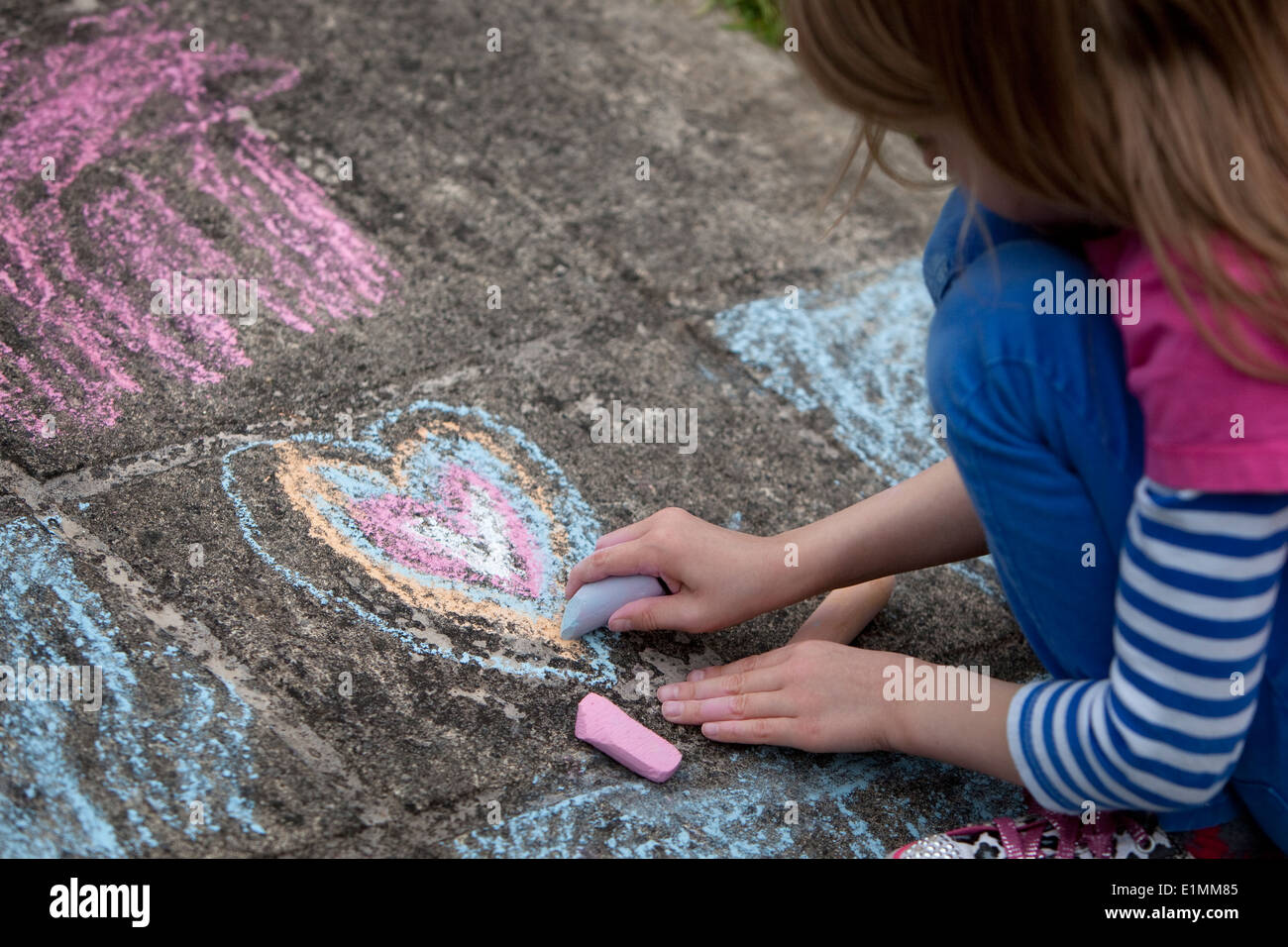 Girl drawing a chalk heart on a concrete sidewalk Stock Photo - Alamy