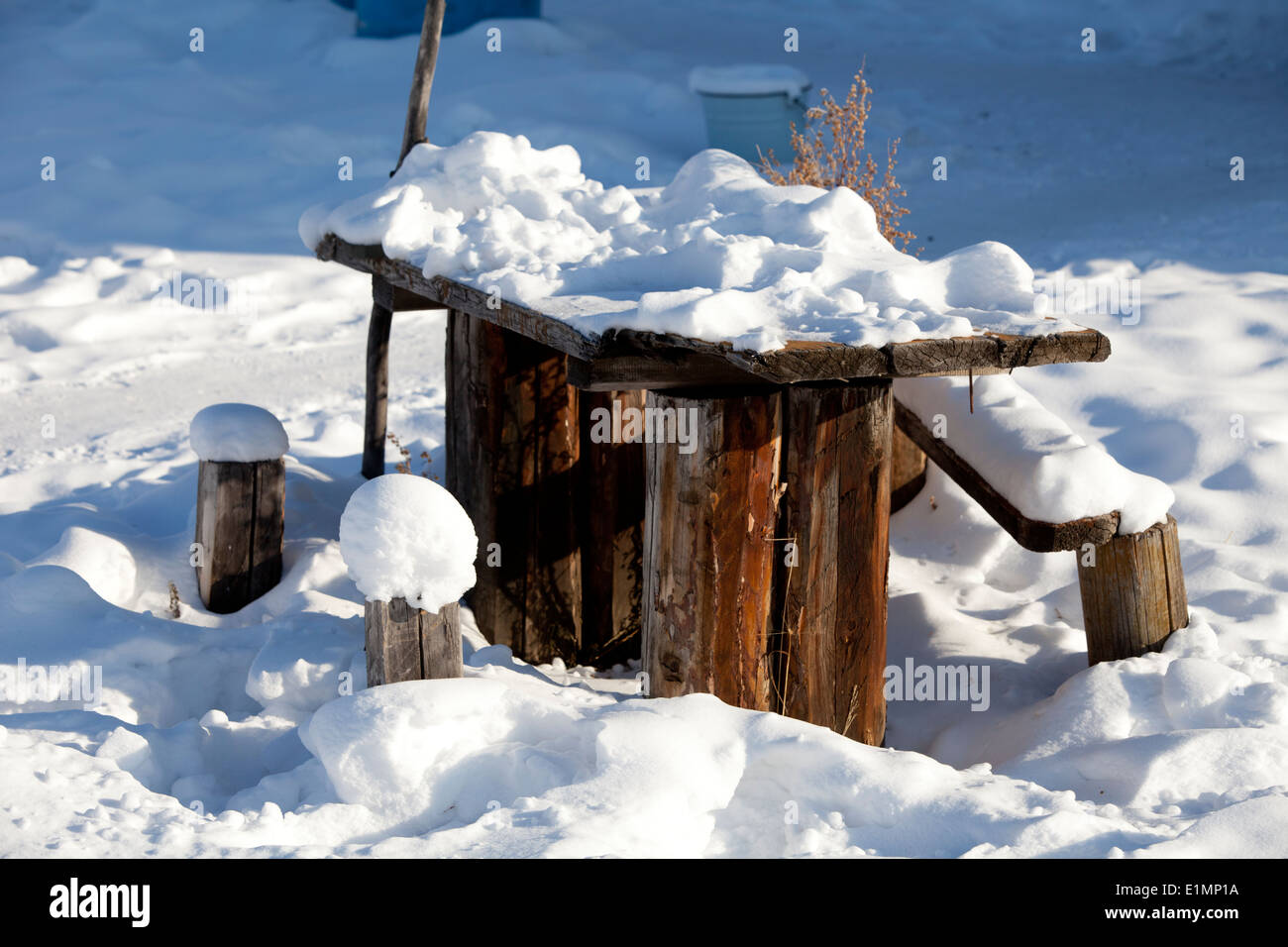 snow covered rustic picnic table in sun Stock Photo