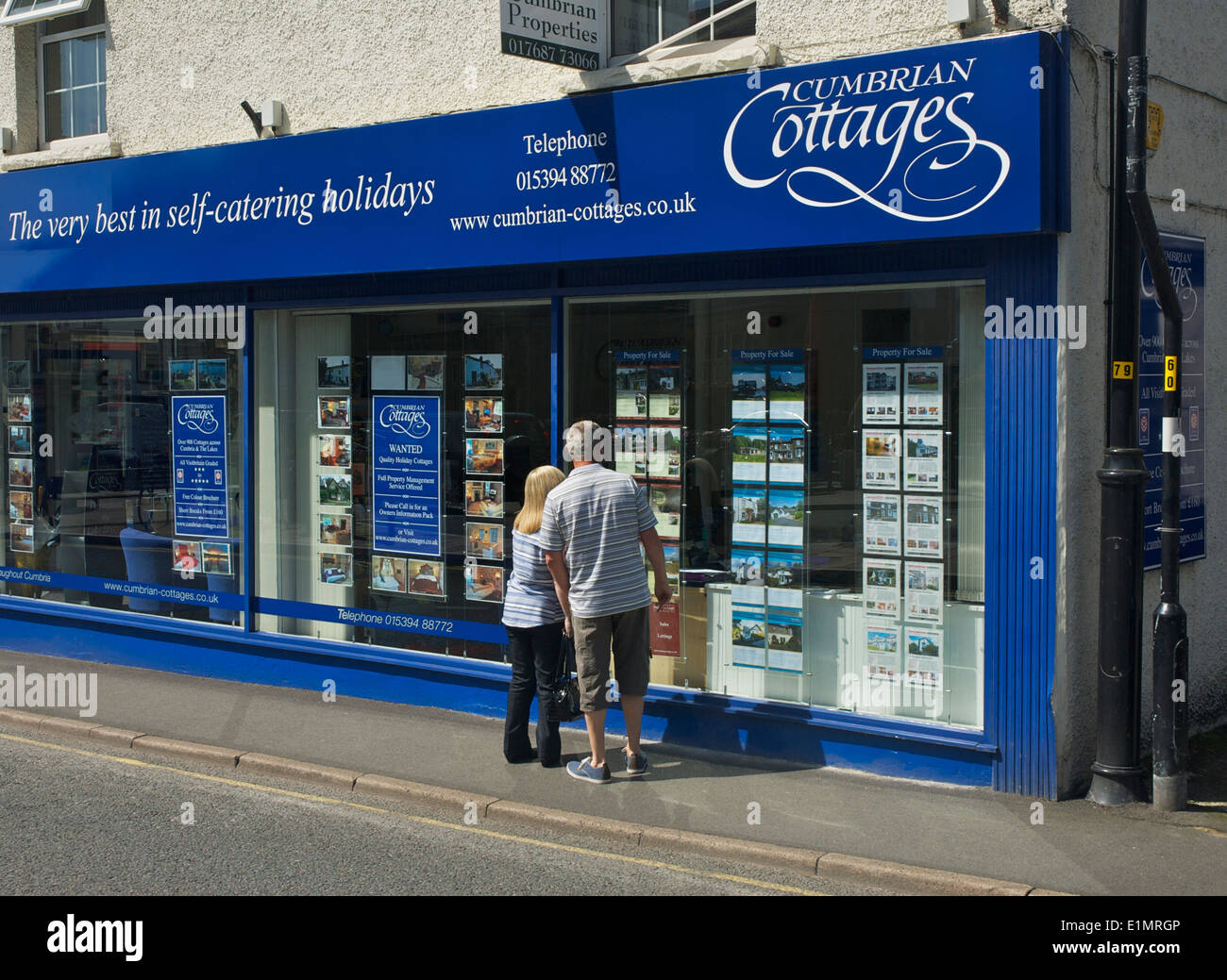 Couple looking at properties in estate agent window (Cumbrian Cottages