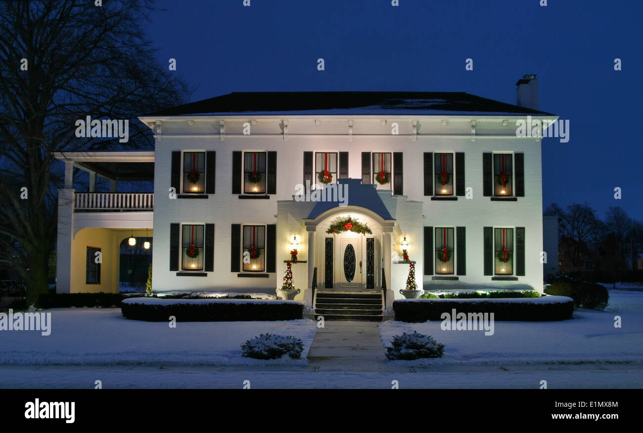 Holiday House. White house at dusk with candles wreaths in the windows  Stock Photo - Alamy