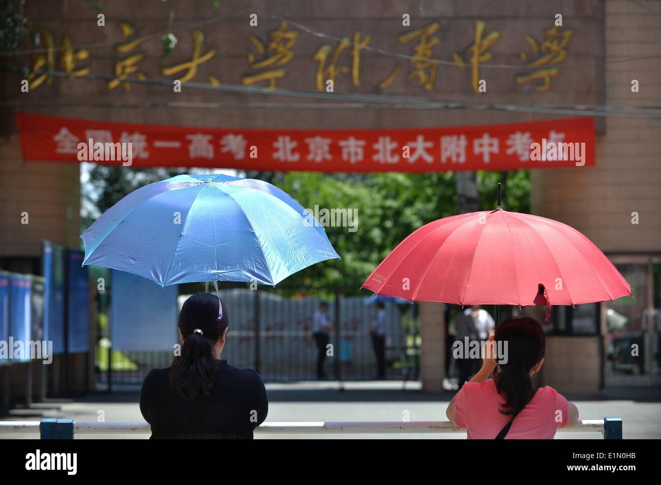 Beijing, China. 7th June, 2014. Two parents brave scorching sun as they wait outside an exam site of the national college entrance exam in Beijing, capital of China, June 7, 2014. The exam, known as the 'gaokao', began on Saturday. A total of 9.39 million people have registered for the exam this year to vie for 6.98 million vacancies in universities and colleges. © Li Xin/Xinhua/Alamy Live News Stock Photo