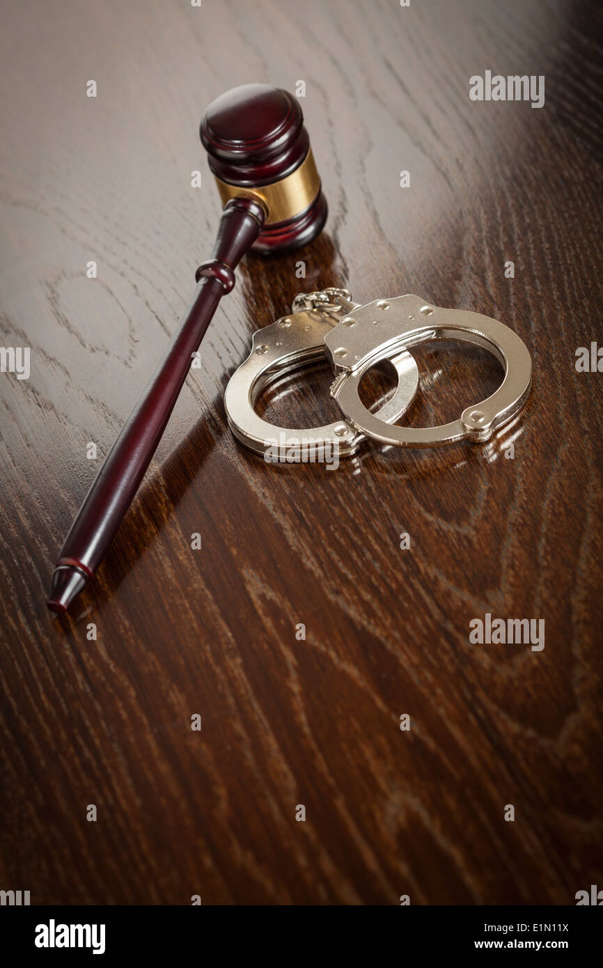 Gavel and Pair of Handcuffs on Wooden Table. Stock Photo