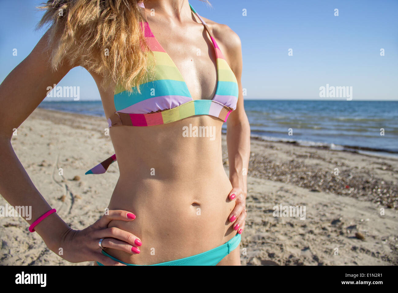 woman bikini body torso colorful sea beach sunny day vacation vivid colors colours 'hands on hips' sporty slim beautiful Stock Photo