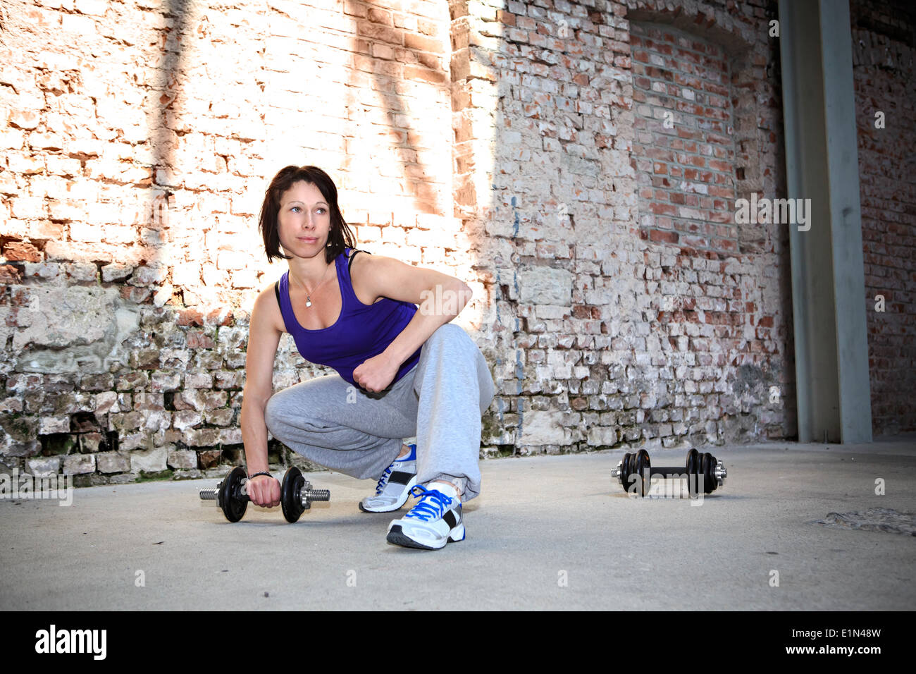 young woman with barbells at fitness exercise in a gym Stock Photo