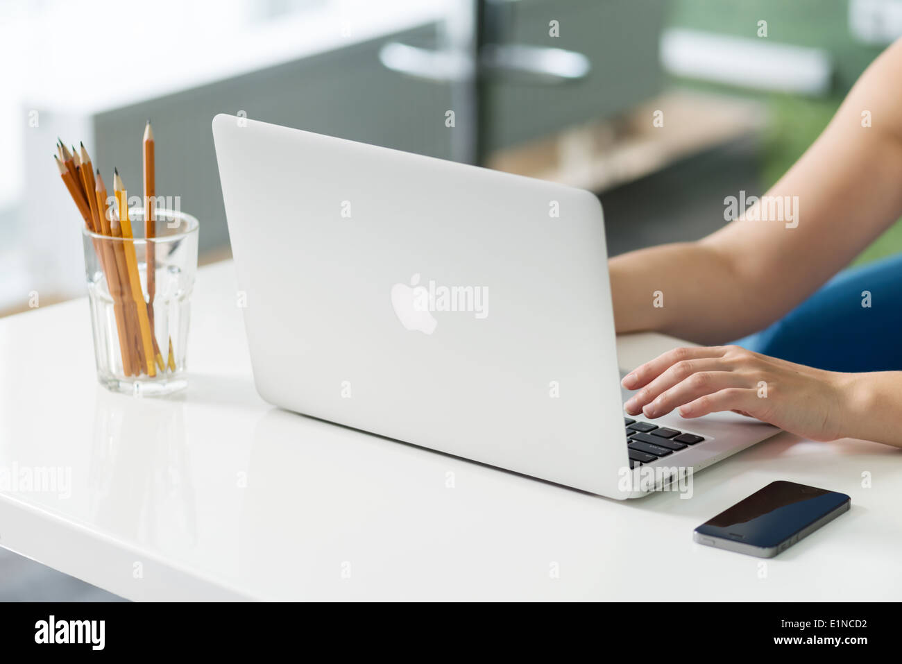 Woman sitting at the desk and typing text on a brand new Apple MacBook Air Stock Photo