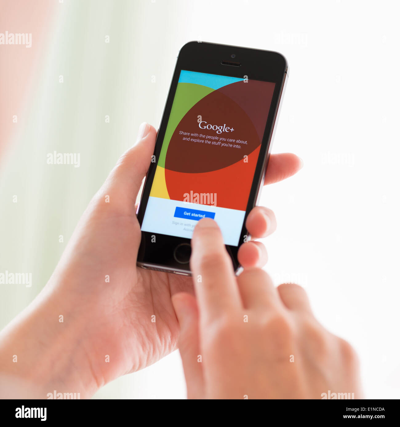 Person holding a brand new Apple iPhone 5S with Google+ application on a screen Stock Photo