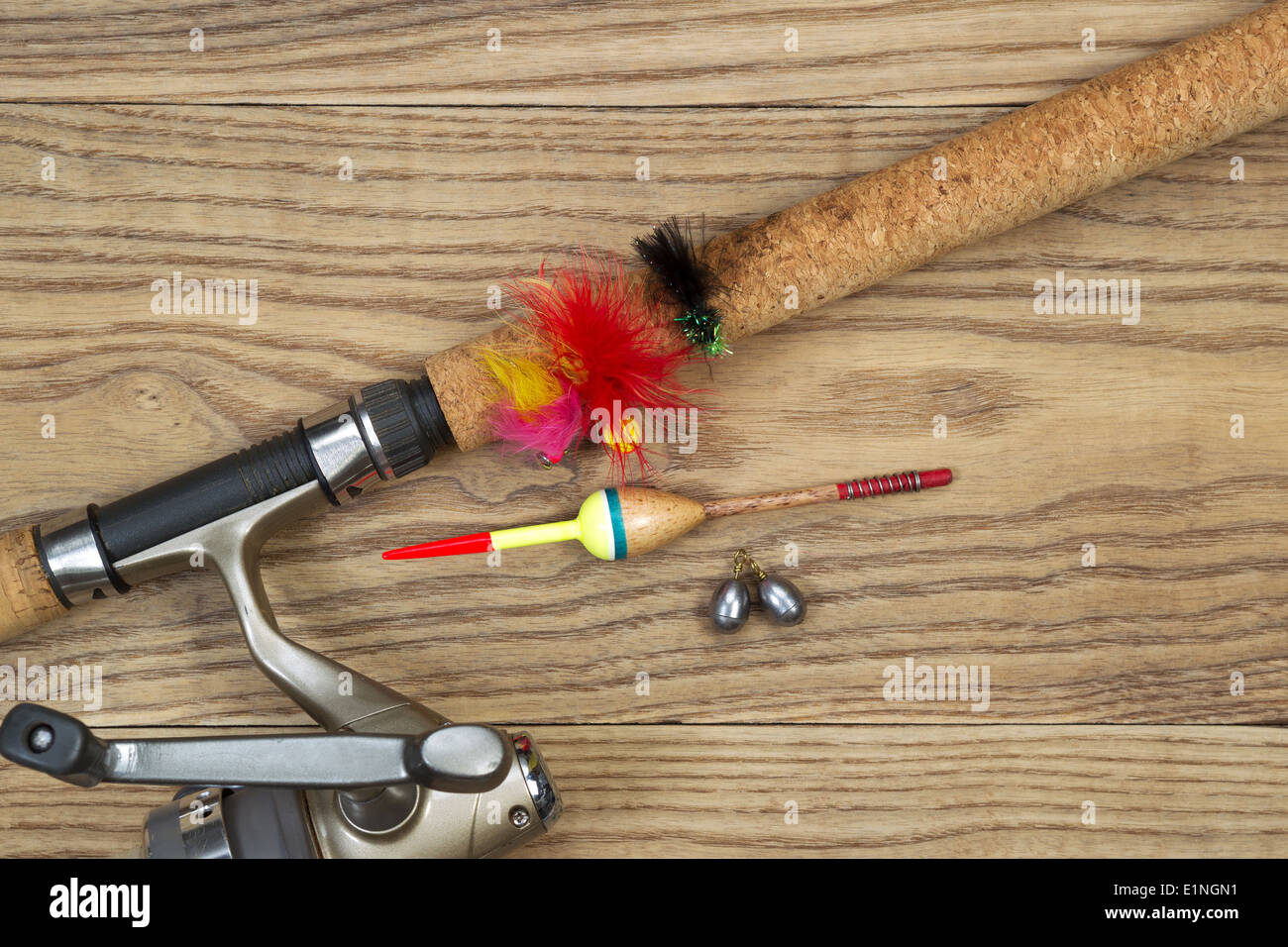 Horizontal top view photo of fishing lures, bobbers, sinkers, cork pole handle and part of reel on faded wood Stock Photo
