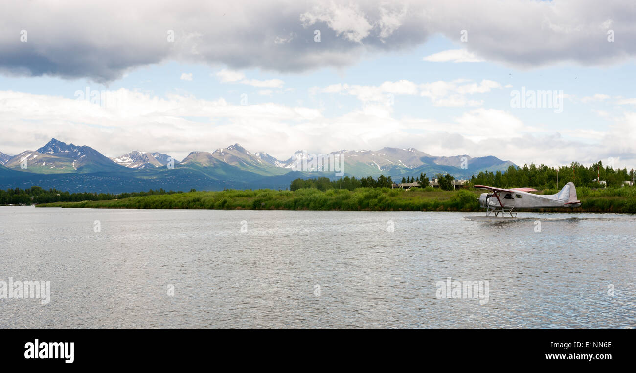 A bush plane performs take off in Alaska with Chugach Mountains in the ...