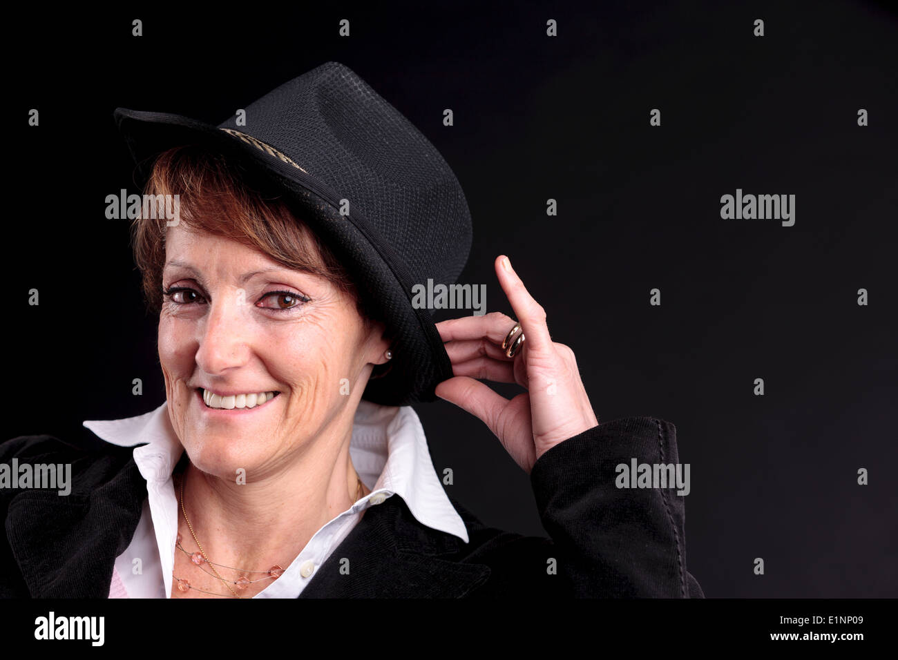 an old white woman smiling while holding up a black fashion hat Stock Photo