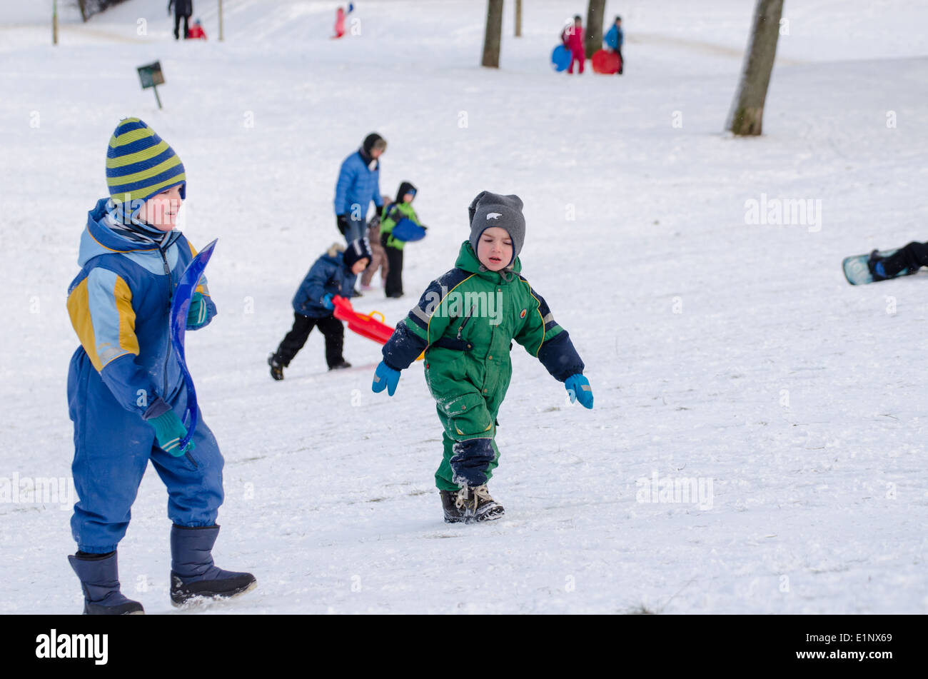 two boy climb uphill with waterproof coverall. Seasonal winter time fun outdoor Stock Photo