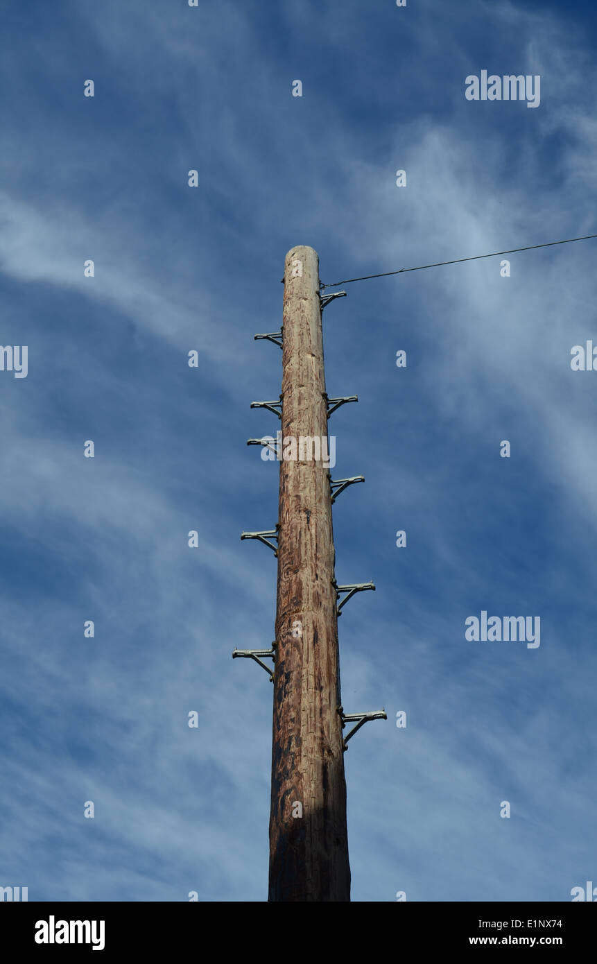 British telegraph pole showing step rungs and line under a blue sky. Stock Photo