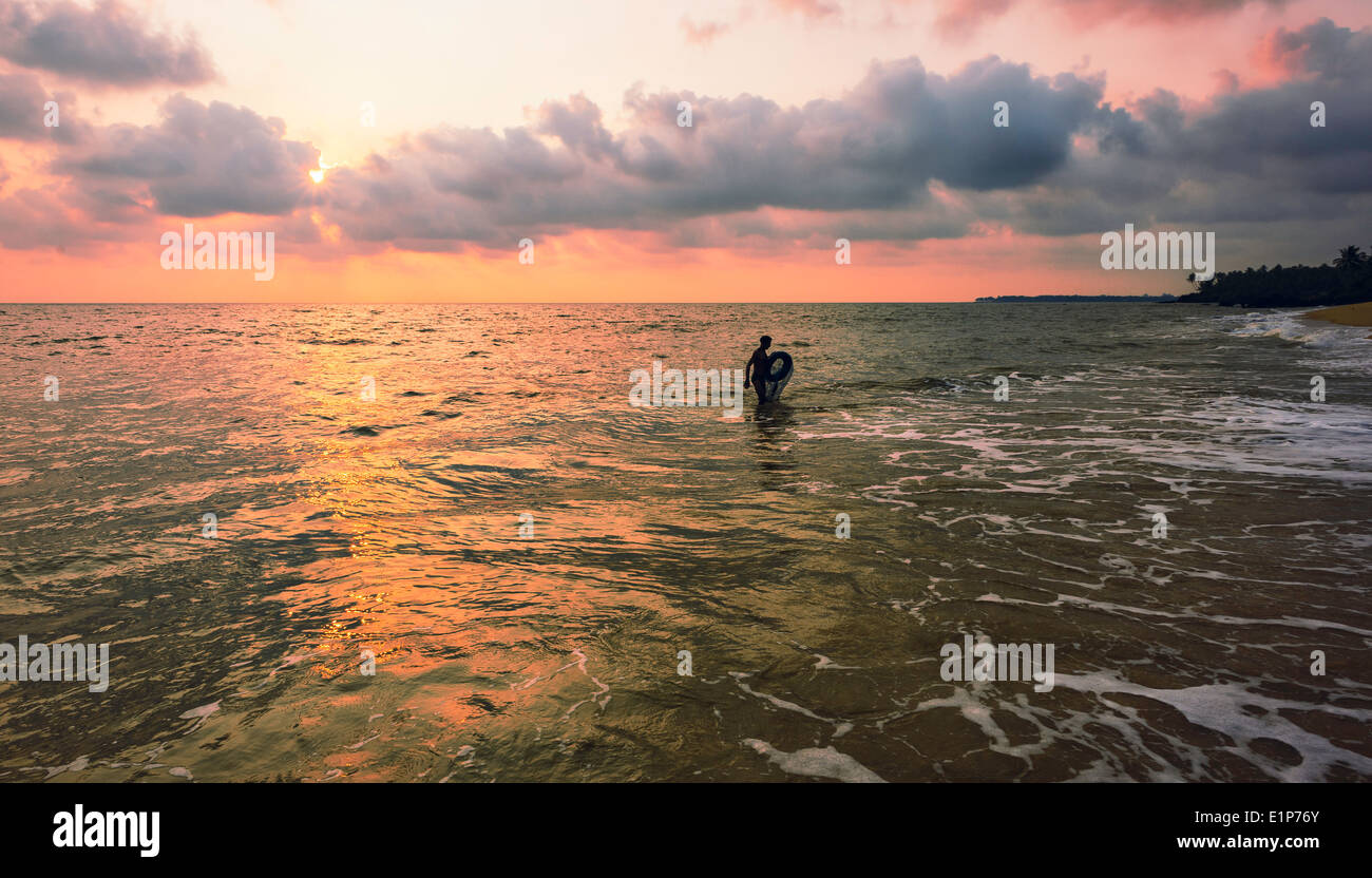 A mollusc trapper emerges from the sea at sunset along Thottada beach on December 02, 2011 near Kannur, Kerala, India. Stock Photo