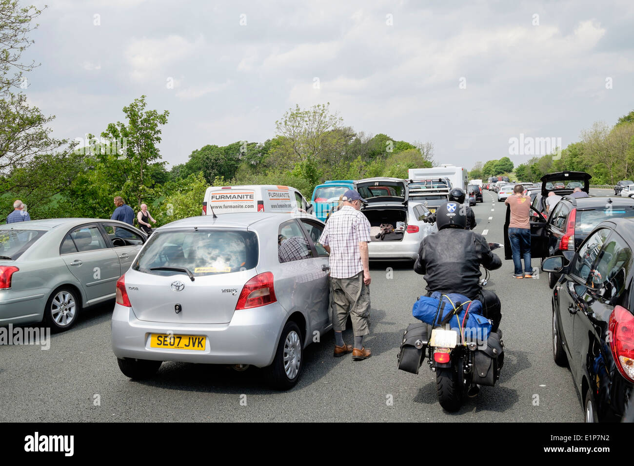 Motorbikes weaving through stationary vehicles in a traffic jam with