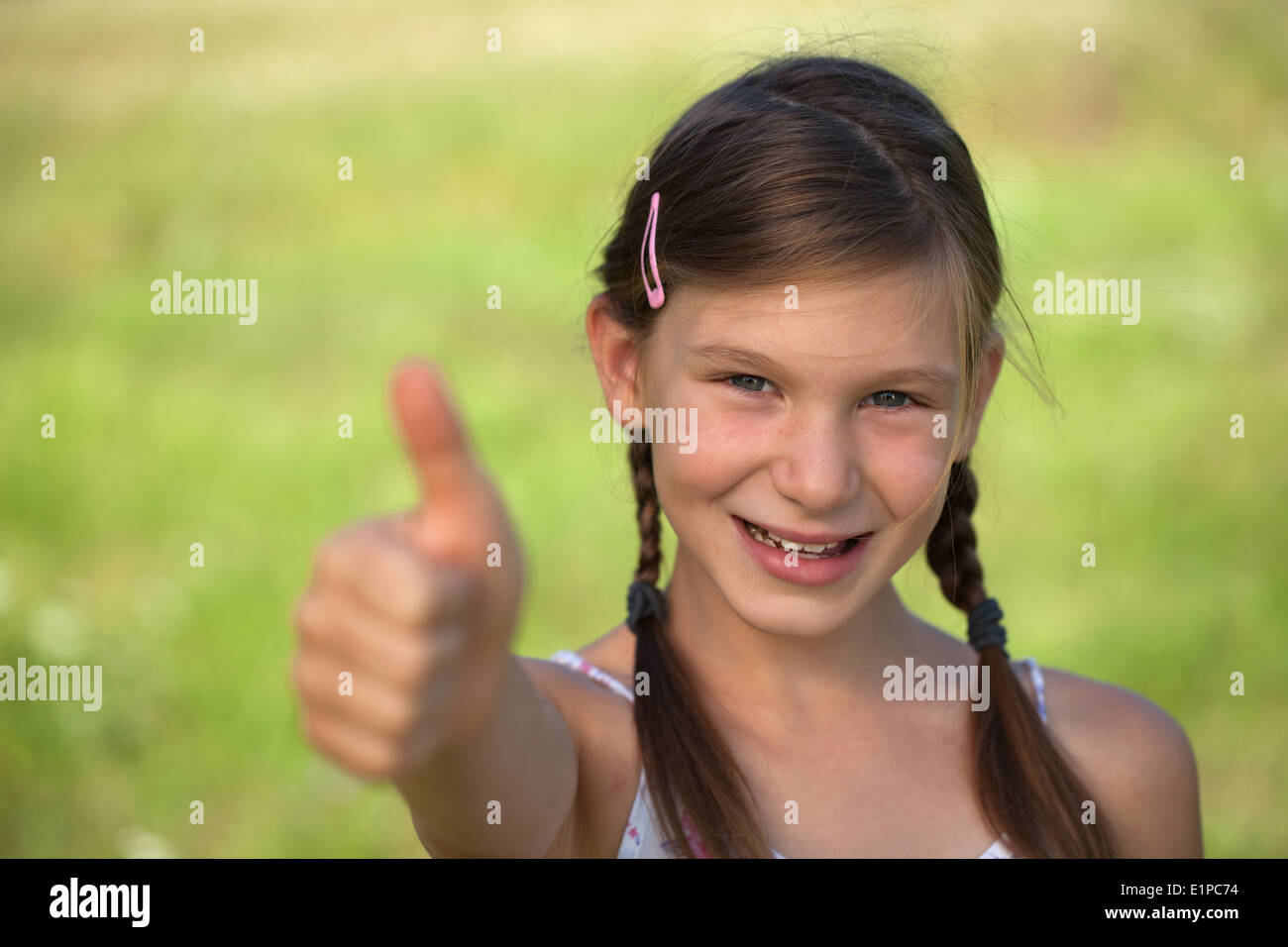 Happy smiling young girl with braids giving thumbs up Stock Photo - Alamy