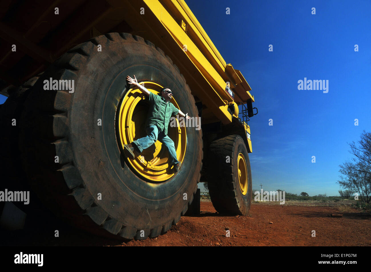 Man climbing on enormous wheel of haulpak mining truck, Newman, Pilbara region, Western Australia. No MR Stock Photo