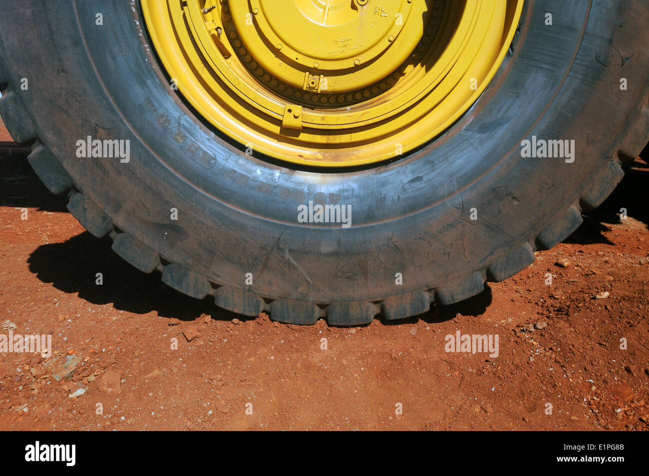 Wheel and tyre of enormous haulpak mining truck on red iron ore-containing earth, Pilbara region, Western Australia. No PR Stock Photo