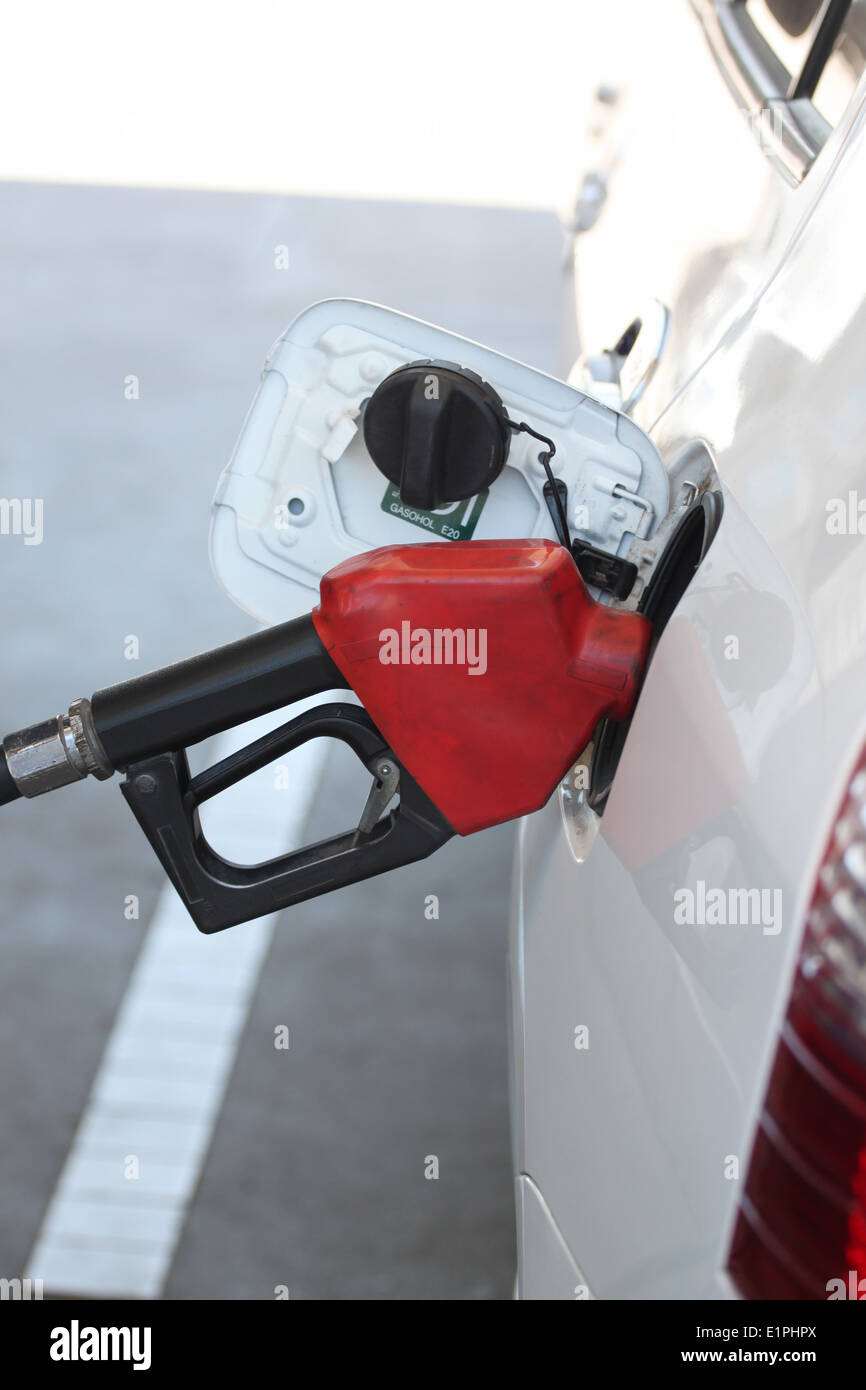 Red fuel nozzle in pouring to car on gas station. Stock Photo