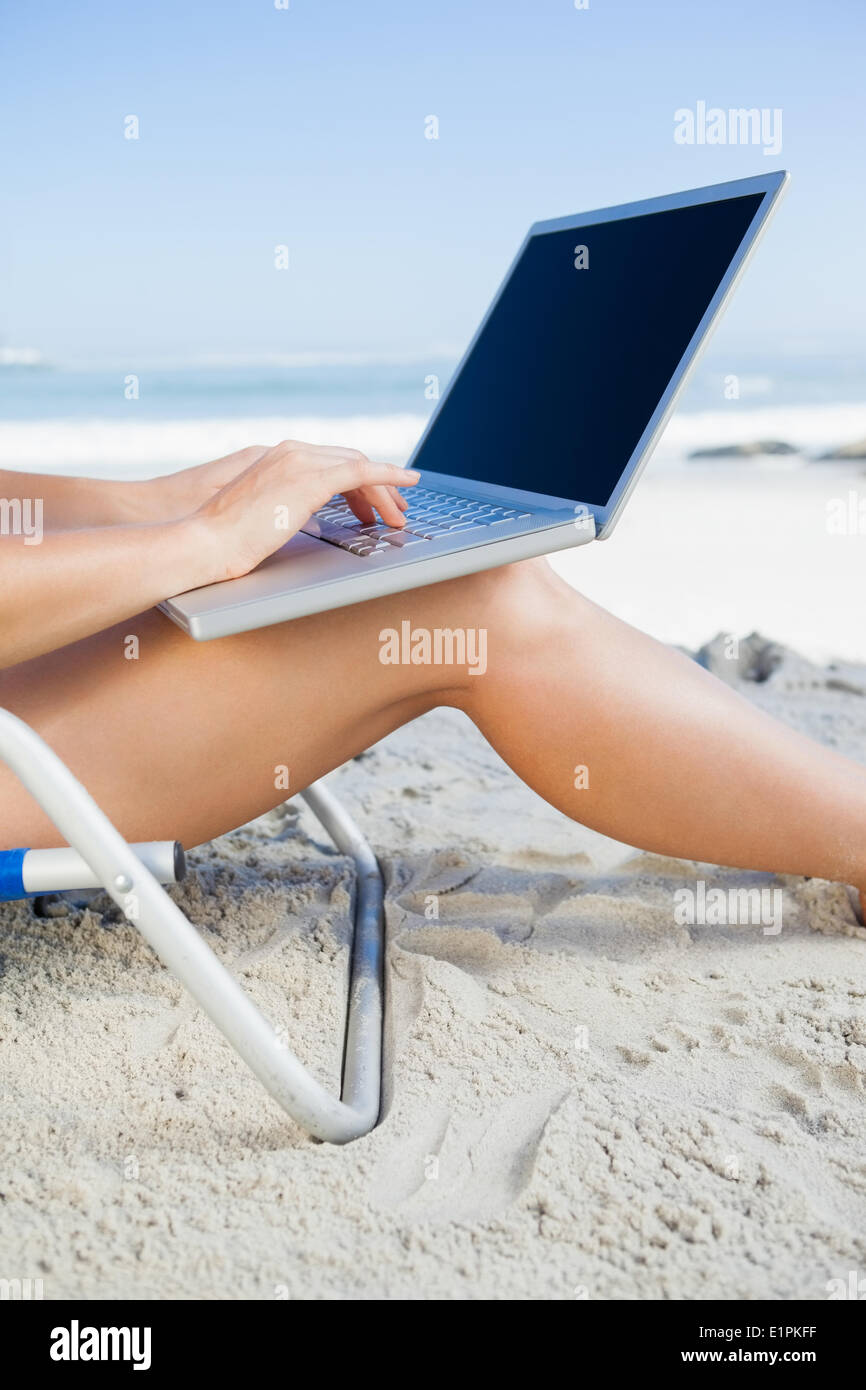 Woman sitting on beach using her laptop Stock Photo