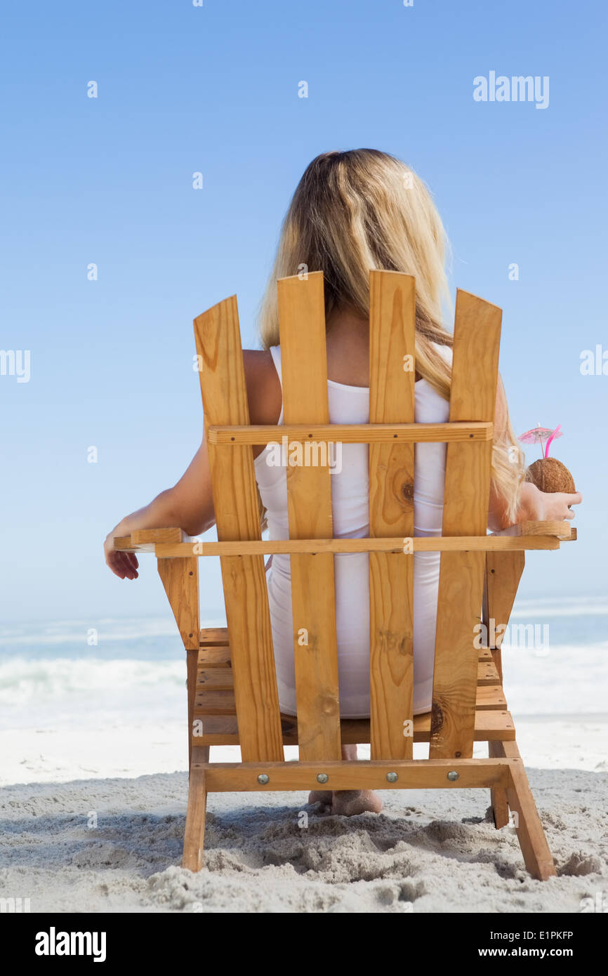 Pretty blonde sitting in deck chair holding coconut drink Stock Photo