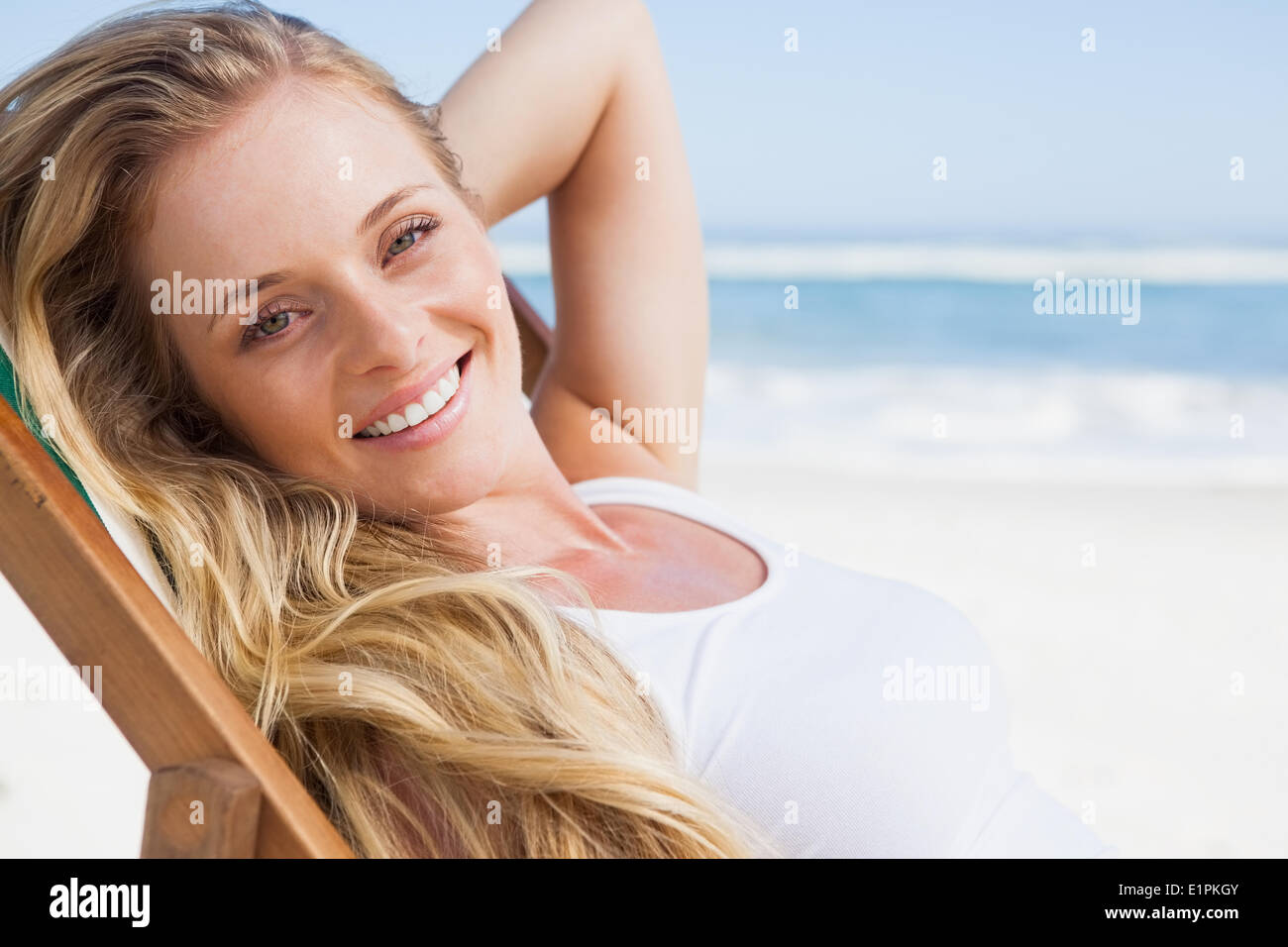Gorgeous blonde sitting at the beach smiling at camera Stock Photo - Alamy