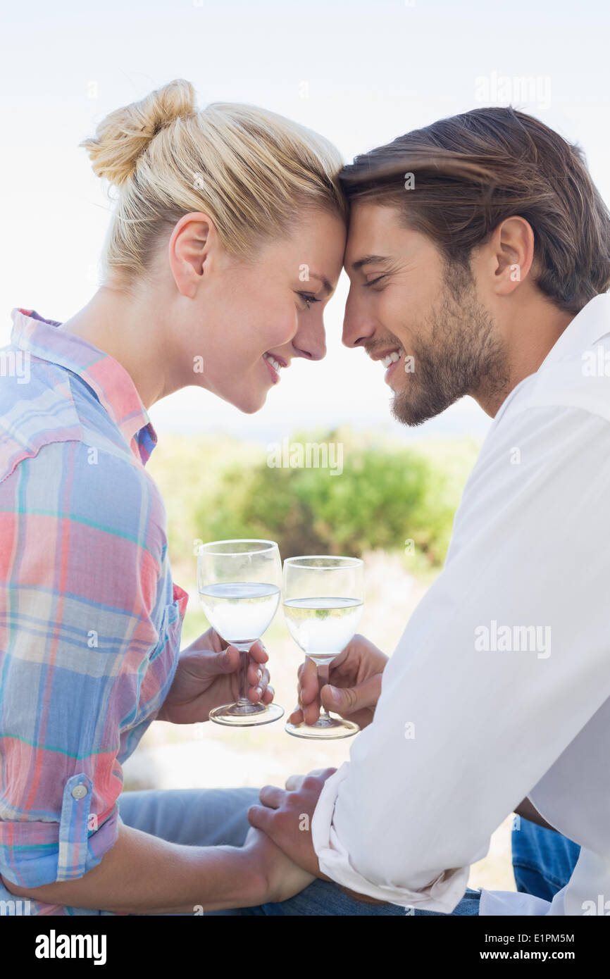 Happy young couple sitting in the garden enjoying wine together Stock Photo