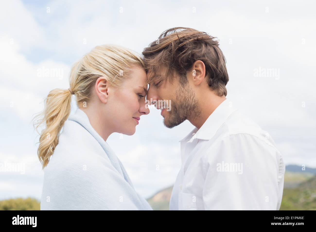 Cute smiling couple standing outside facing each other Stock Photo