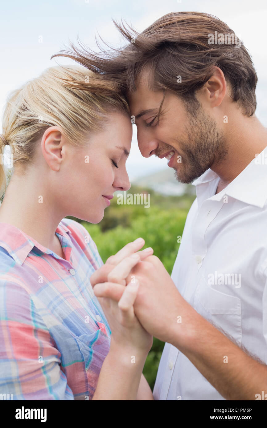 Cute affectionate couple standing outside holding hands Stock Photo