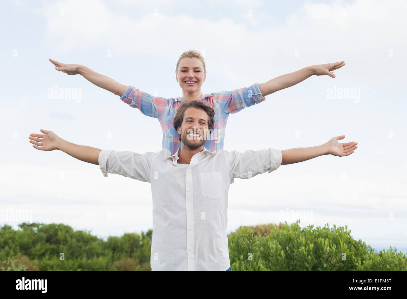 Cute couple standing outside with arms outstretched Stock Photo