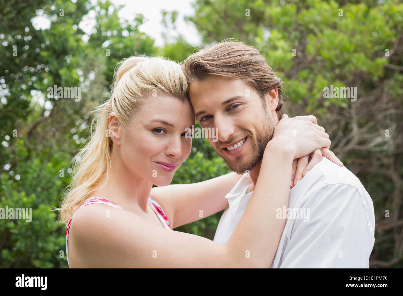 Cute couple standing outside hugging smiling at camera Stock Photo