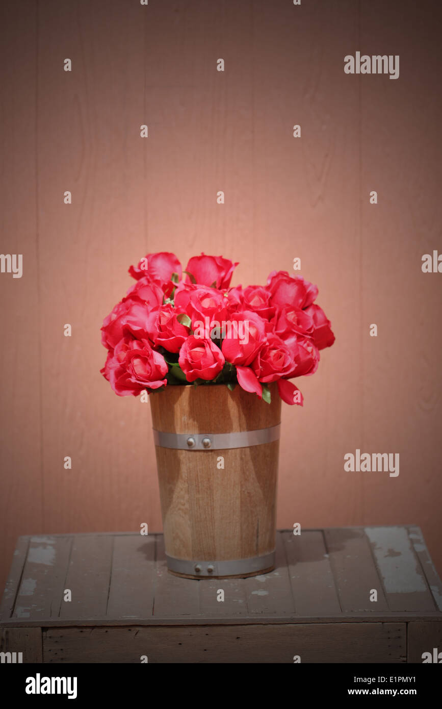 Red rose in wooden vase on brown background. Stock Photo