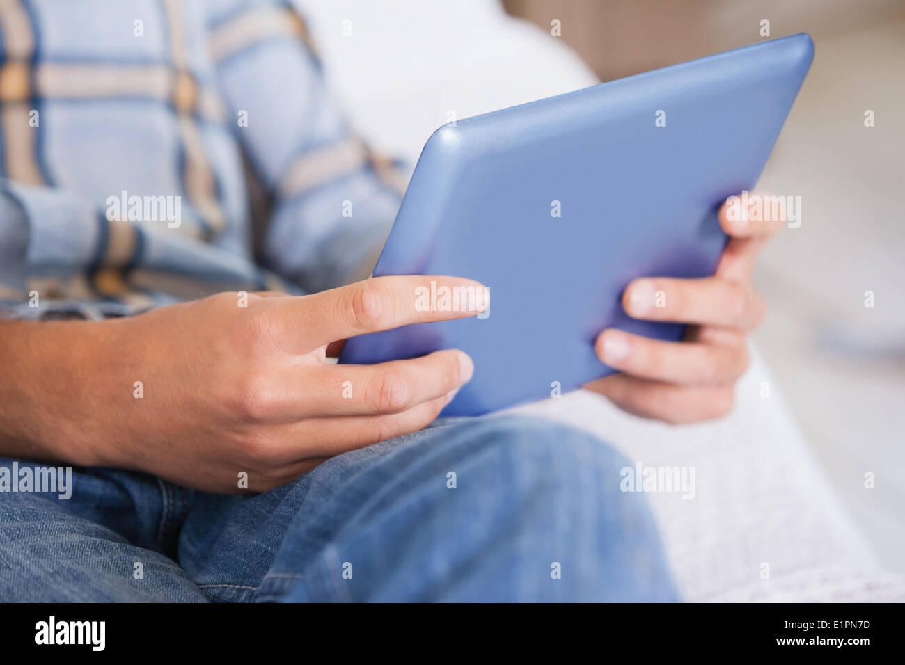 Man lying on couch using tablet pc Stock Photo
