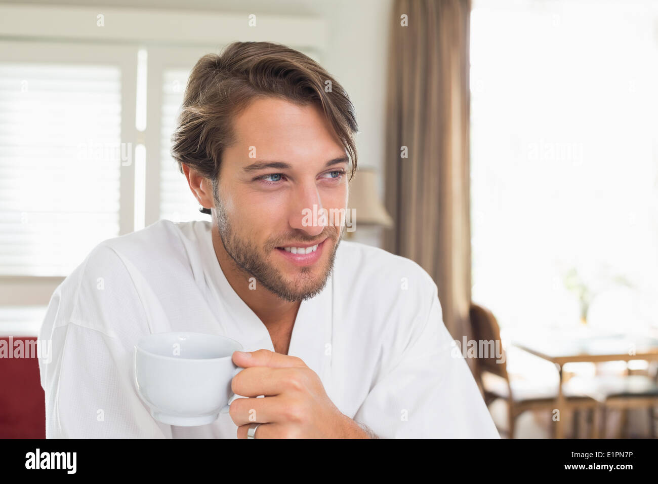 Handsome man having breakfast in his bathrobe drinking coffee Stock Photo