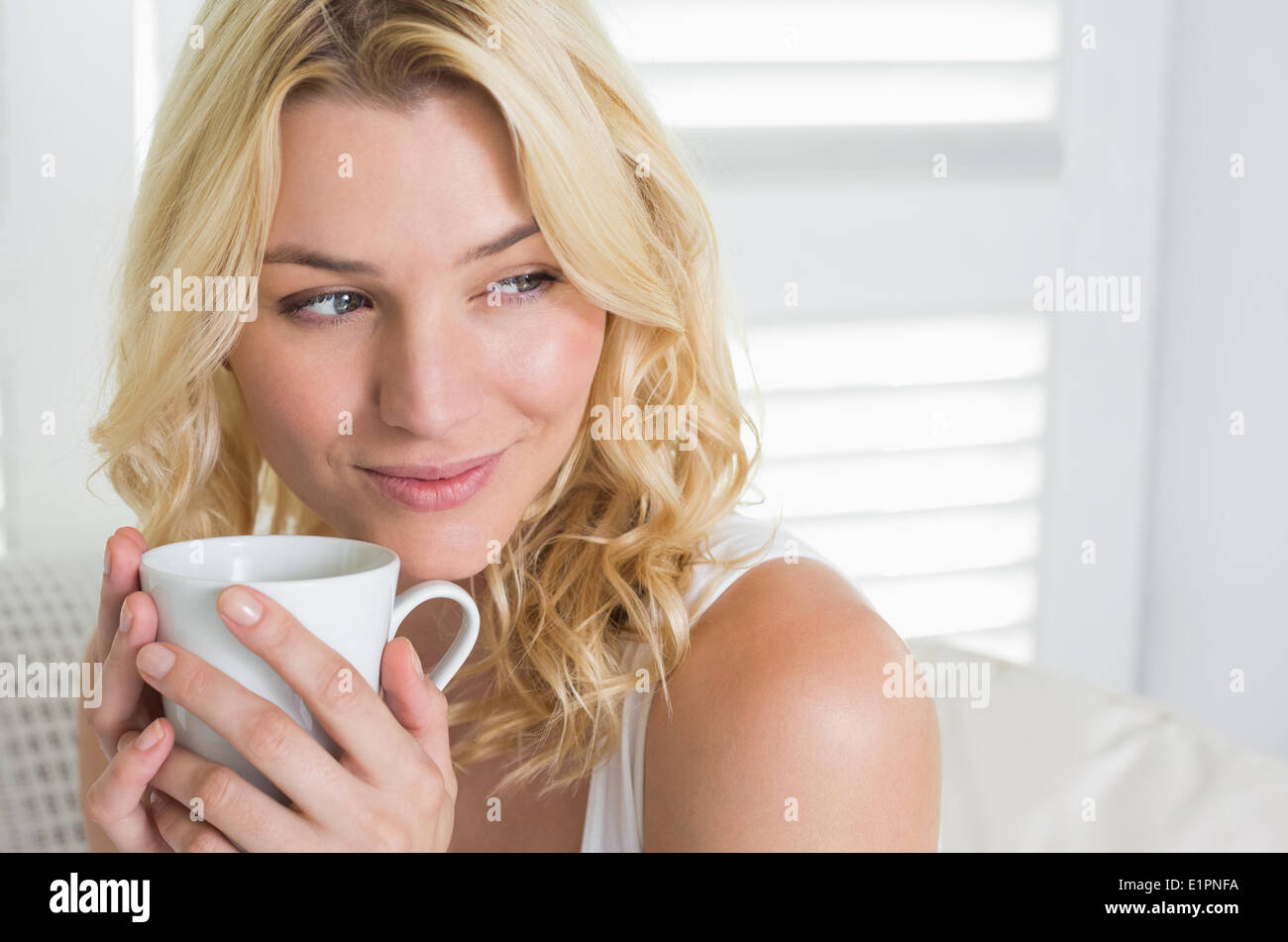 Happy blonde relaxing on the couch with a coffee Stock Photo - Alamy