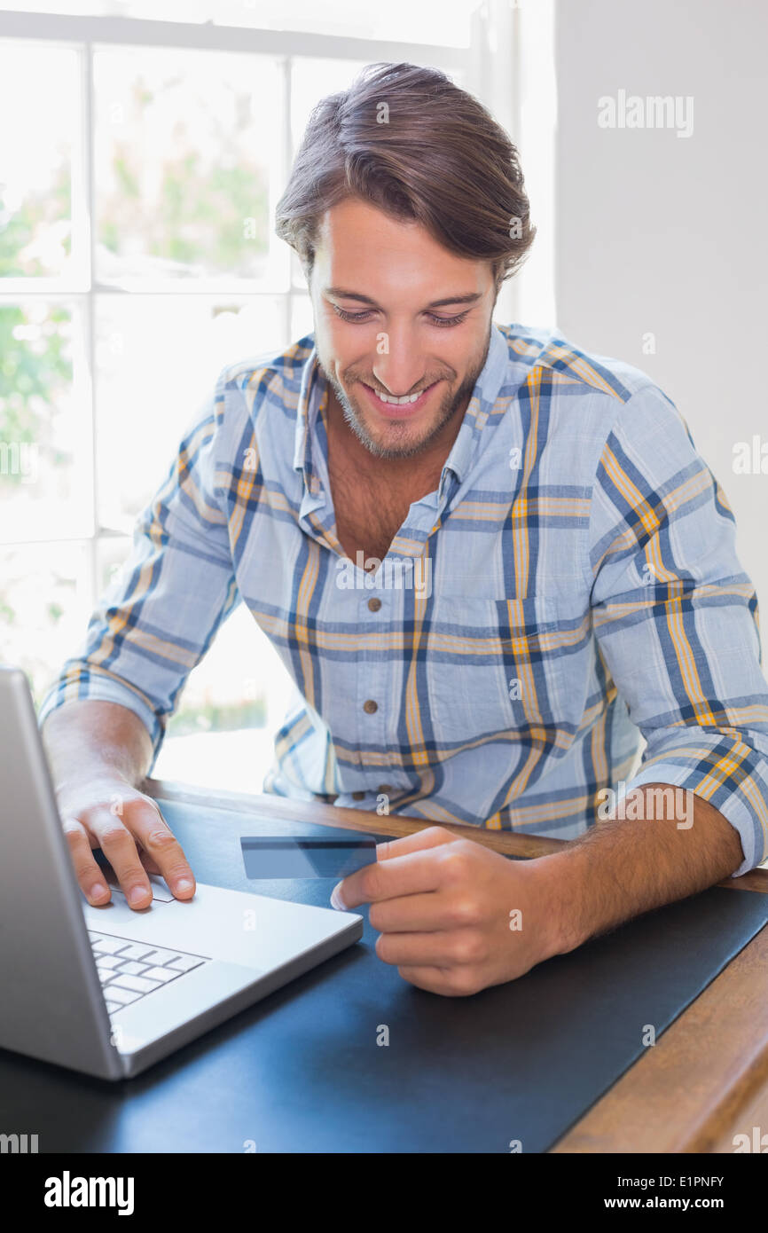 Smiling casual man using laptop to shop online Stock Photo