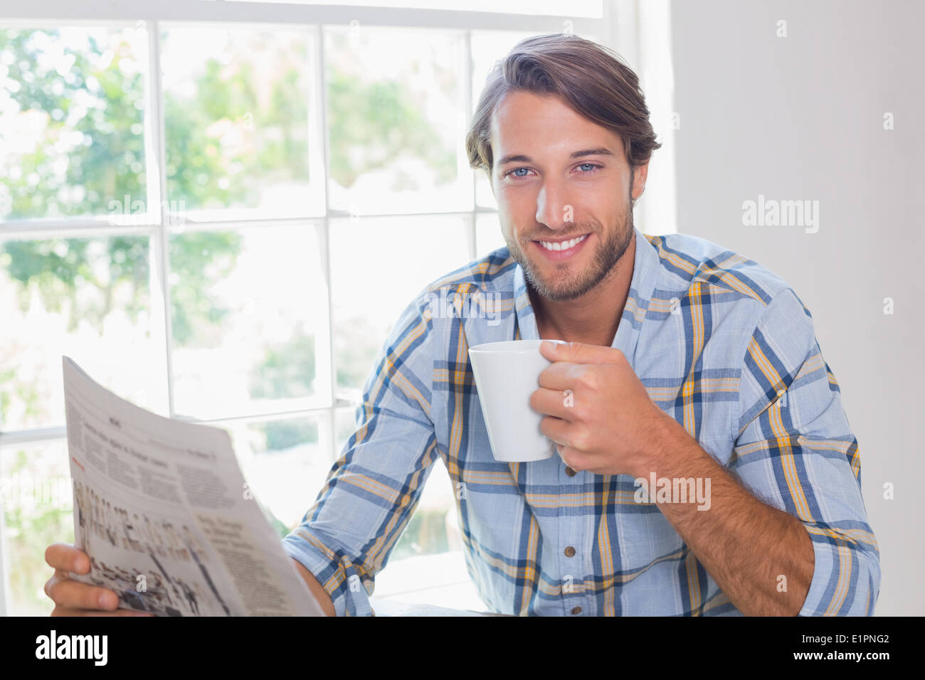 Casual smiling man having coffee while reading newspaper Stock Photo