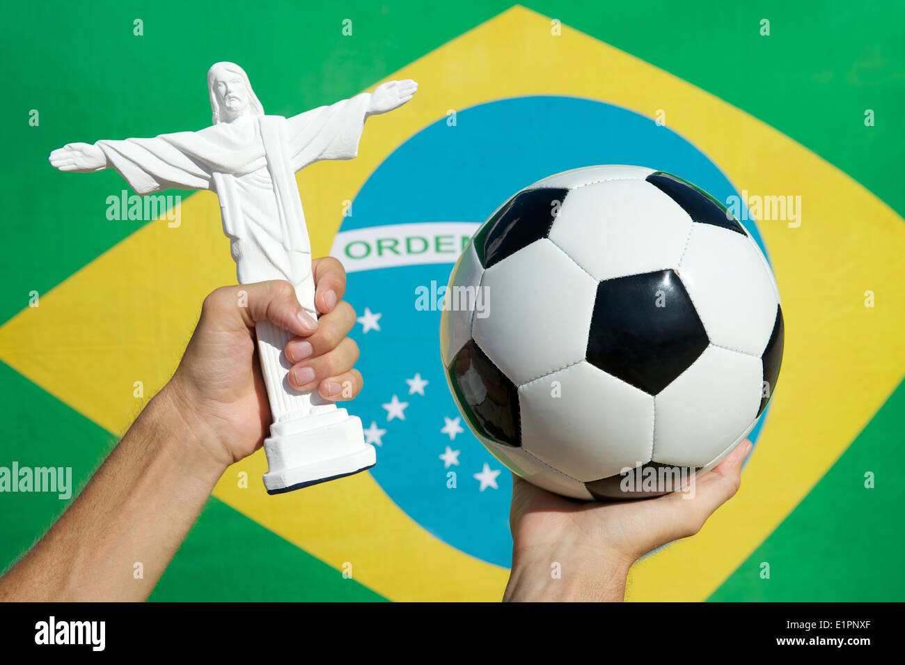 Hands holding football soccer ball and souvenir statue of Corcovado Cristo Redentor in front of Brazilian flag Stock Photo