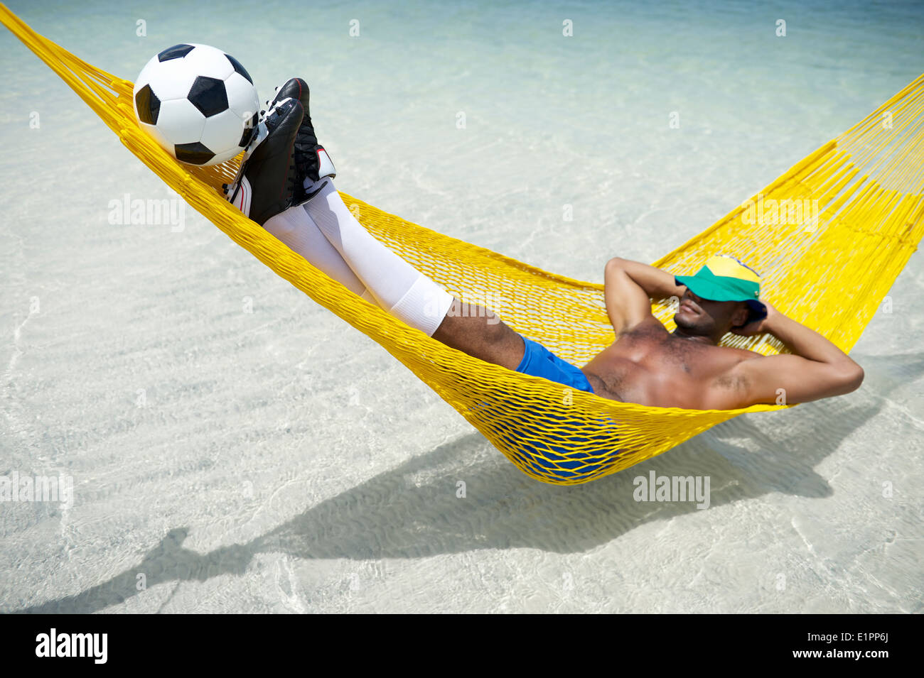 Brazilian footballer relaxing in beach hammock with a soccer ball