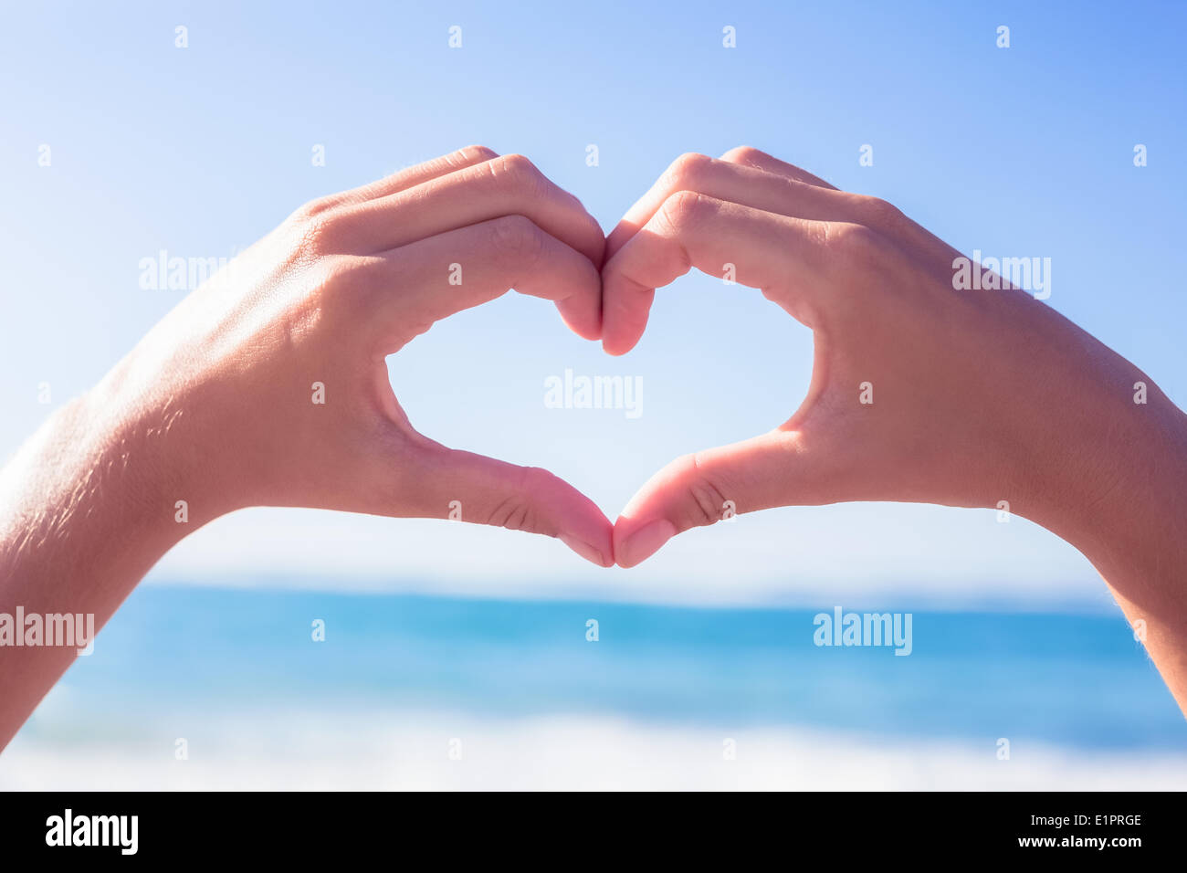 Hands making heart shape on the beach Stock Photo
