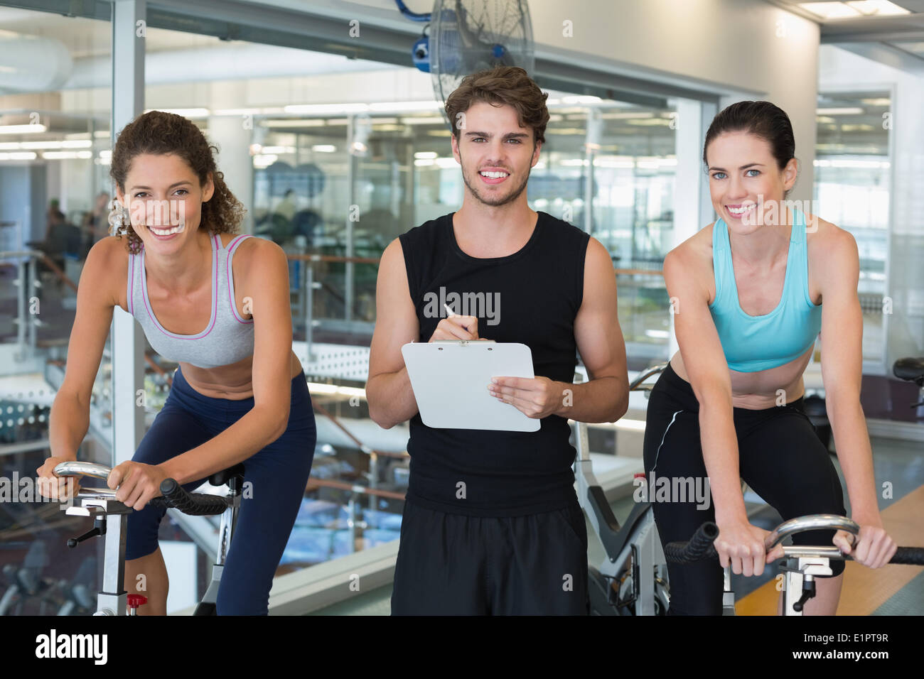 Fit women in a spin class with trainer smiling at camera Stock Photo ...