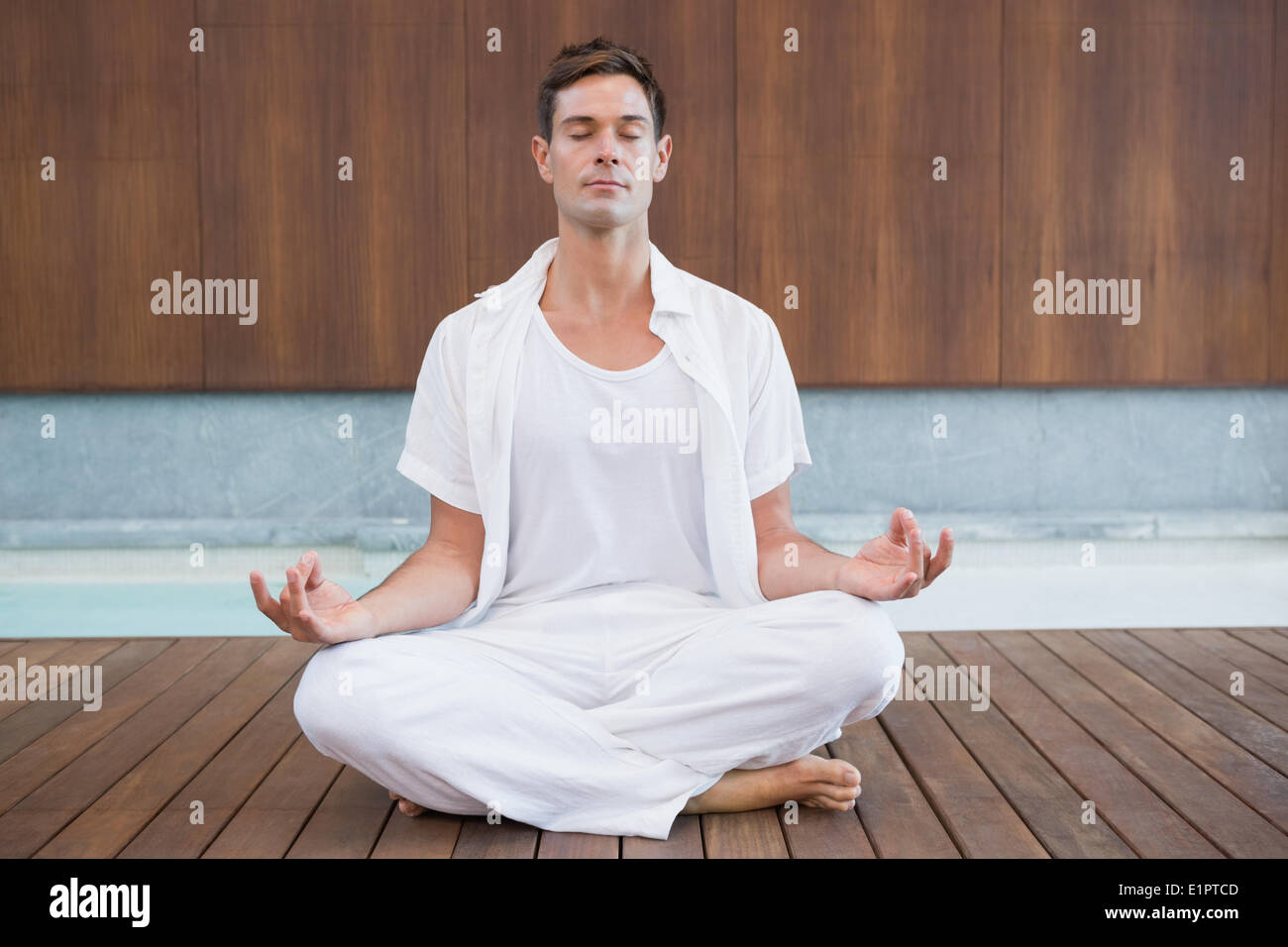Handsome man in white meditating in lotus pose Stock Photo