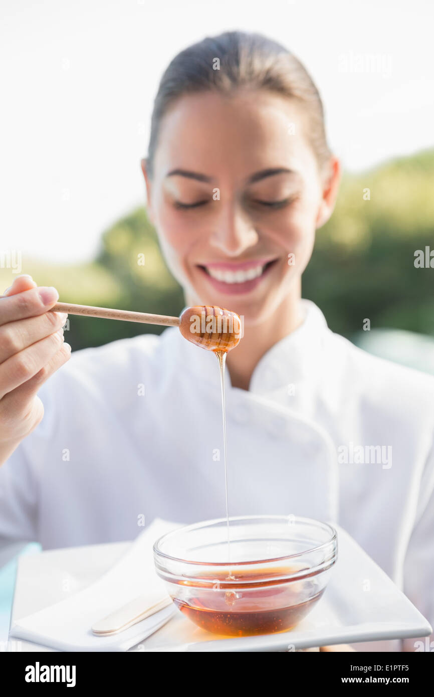 Smiling beauty therapist holding plate with honey Stock Photo