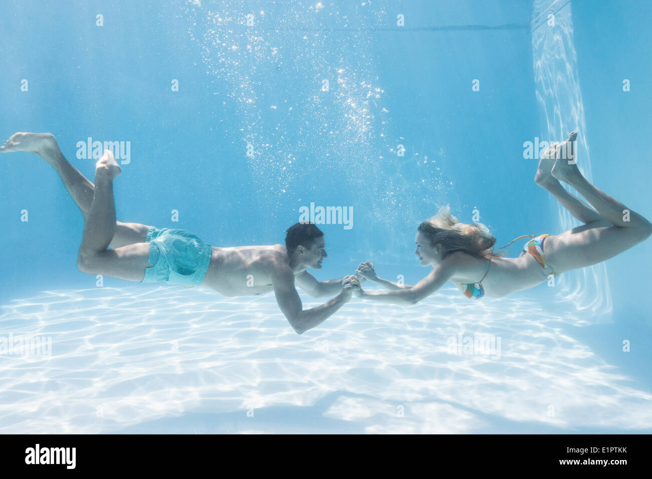 Cute couple holding hands underwater in the swimming pool Stock Photo