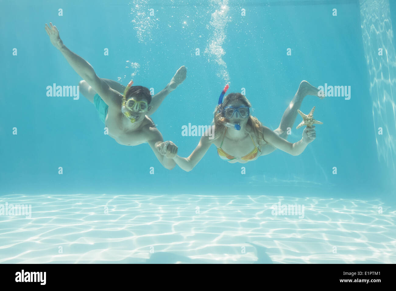 Cute couple underwater in the swimming pool with snorkel and starfish Stock Photo