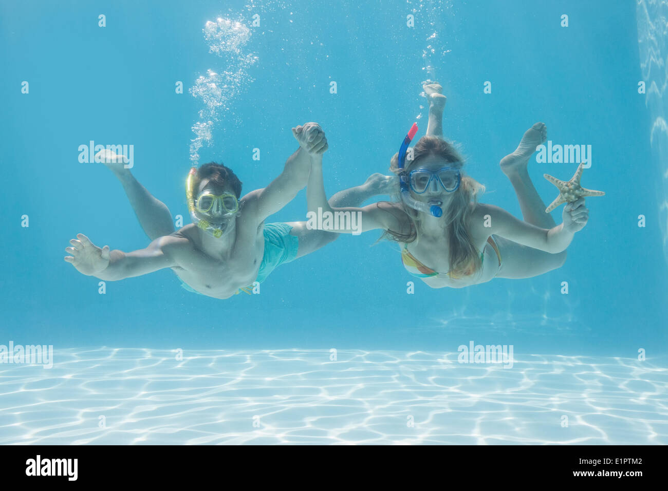 Cute couple underwater in the swimming pool with snorkel and starfish Stock Photo