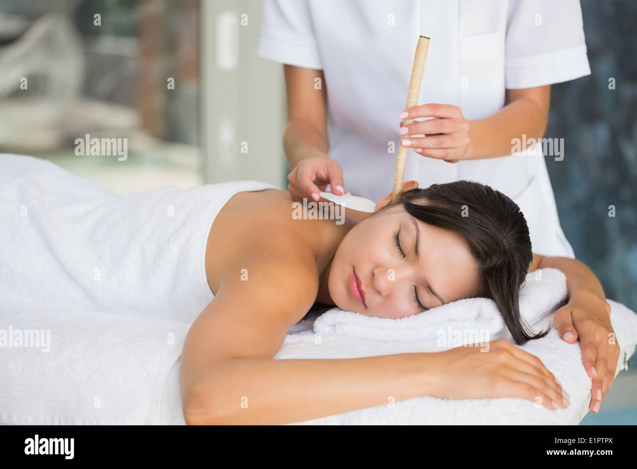 Relaxed brunette getting an ear candling treatment Stock Photo