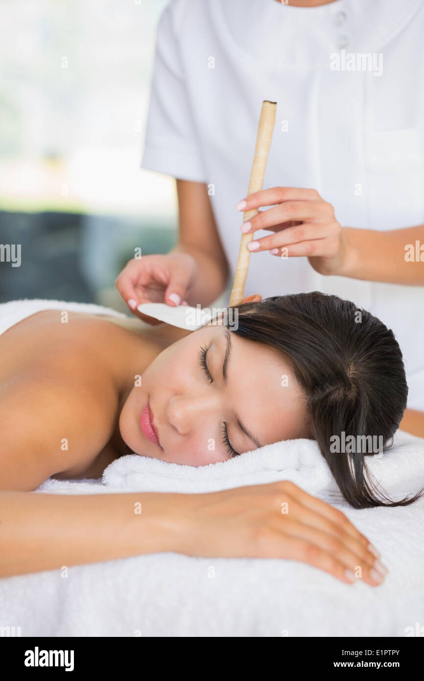 Relaxed brunette getting an ear candling treatment Stock Photo