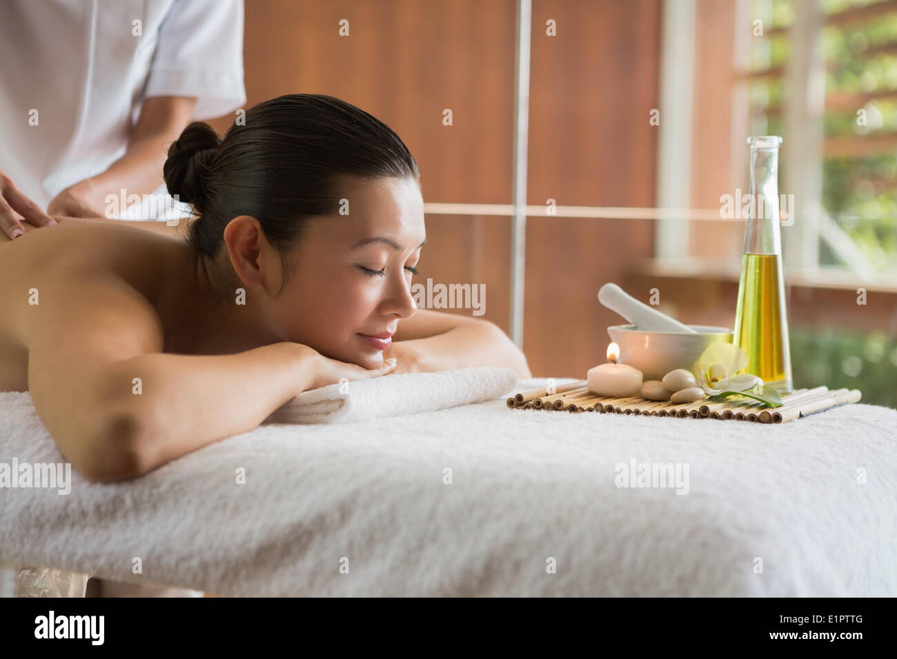 Brunette enjoying a massage with beauty treatments beside Stock Photo