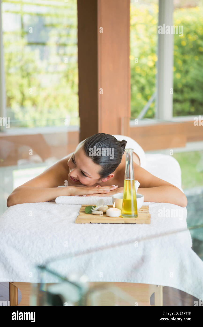 Brunette lying on massage table with tray of beauty treatments Stock Photo